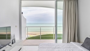 Une chambre d’hôtel moderne dotée d’un balcon, d’un lit, d’une télévision et d’un bureau avec une télécommande.