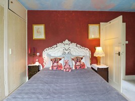 Un dormitorio con una cama grande, un cabecero ornamentado y dos cuadros en la pared.