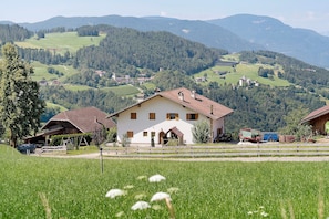 A rural house with a sloped roof, a fenced yard, and a view of the surrounding countryside. - Farmhouse 'Gatterpunerhof' with Mountain View, Shared Terrace and Wi-Fi (Völs am Schlern)