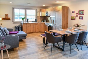 Una cocina moderna con armarios de madera, una mesa de comedor con sillas, un sofá y una ventana con vistas.