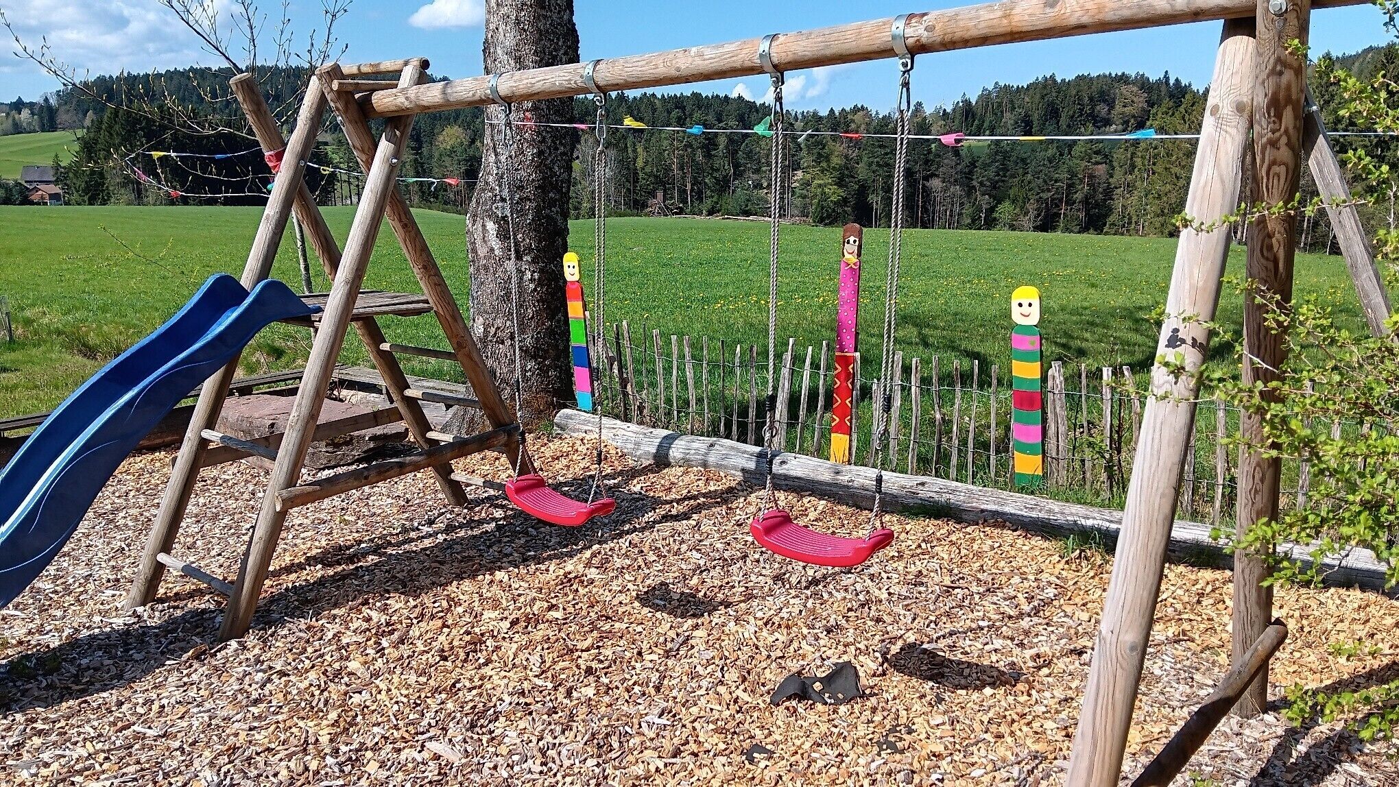 A playground with a slide, swings, and colorful decorations.