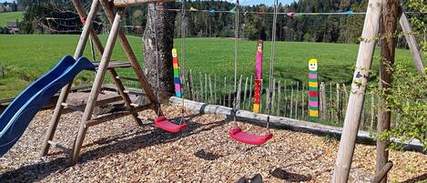 A playground with a slide, swings, and colorful decorations.