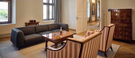 Una sala moderna con un sofá seccional, una mesa de centro de madera, sillones a rayas, un mueble de madera y una lámpara de techo circular grande.
