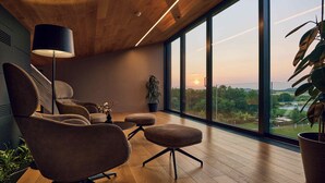 Una sala de estar moderna con un ventanal grande, suelo de madera y techo con vigas a la vista.
