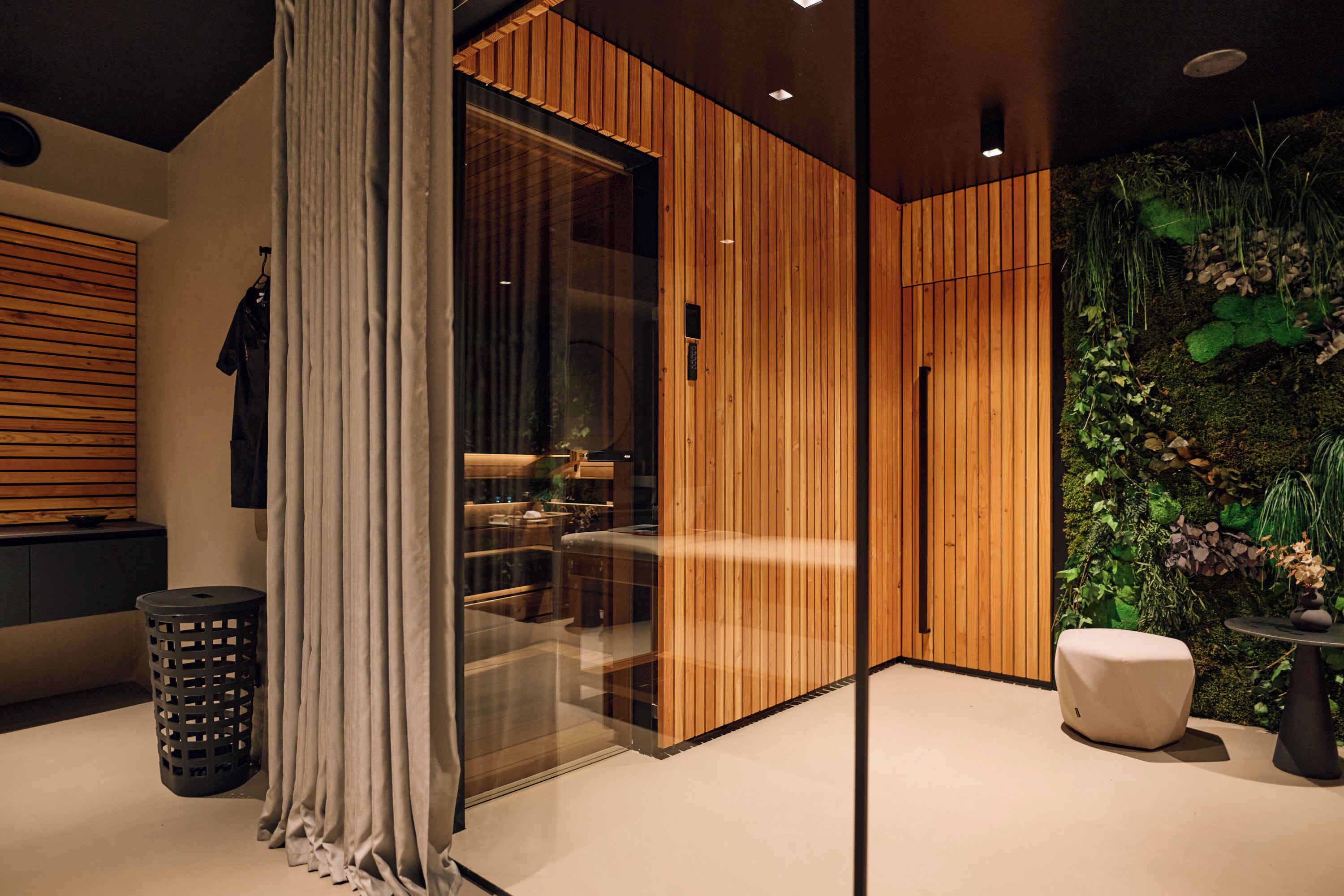 A modern interior with a wooden panel wall, a glass partition, and a green wall with plants.