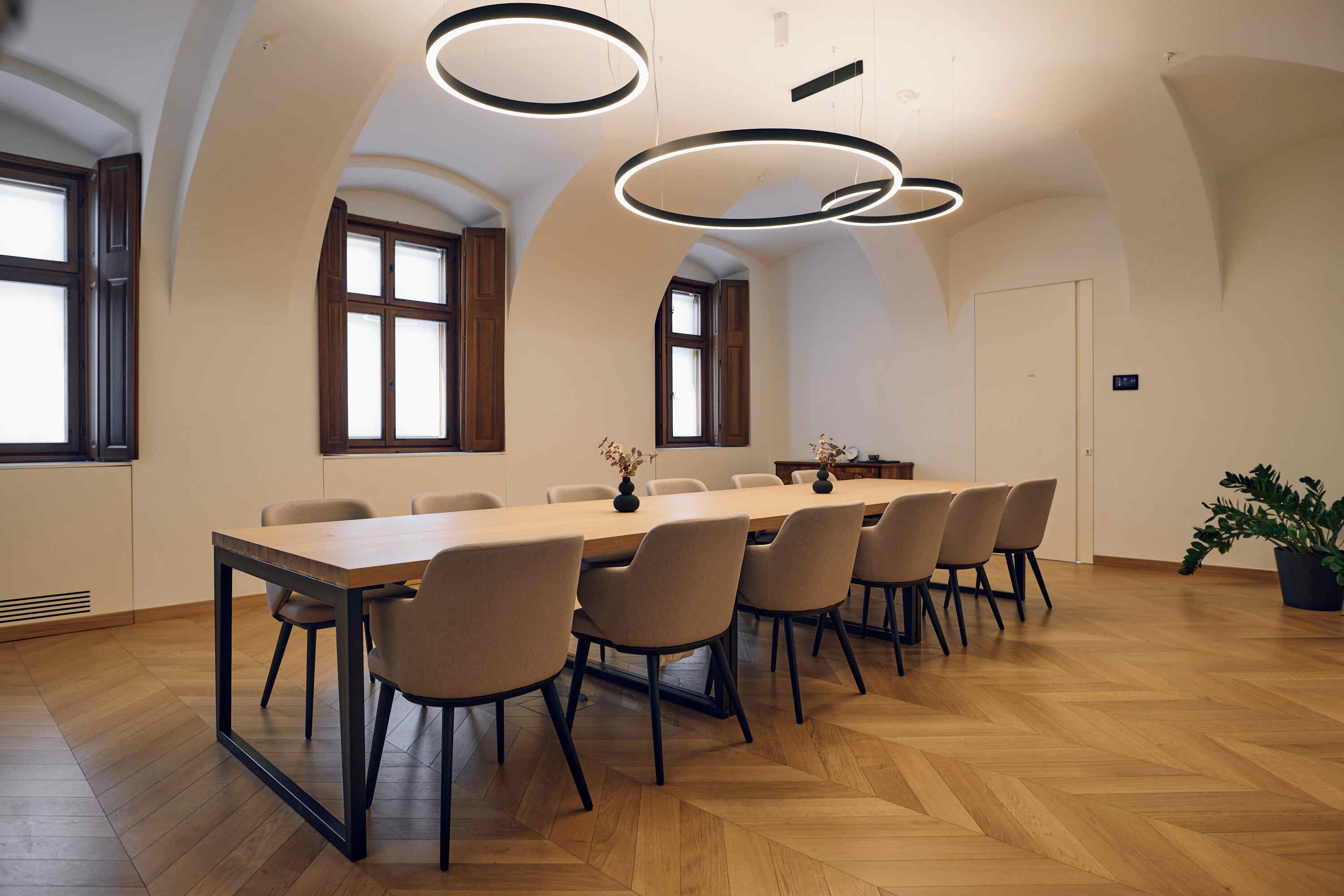 Una sala de conferencias con una larga mesa, varias sillas e iluminación moderna.