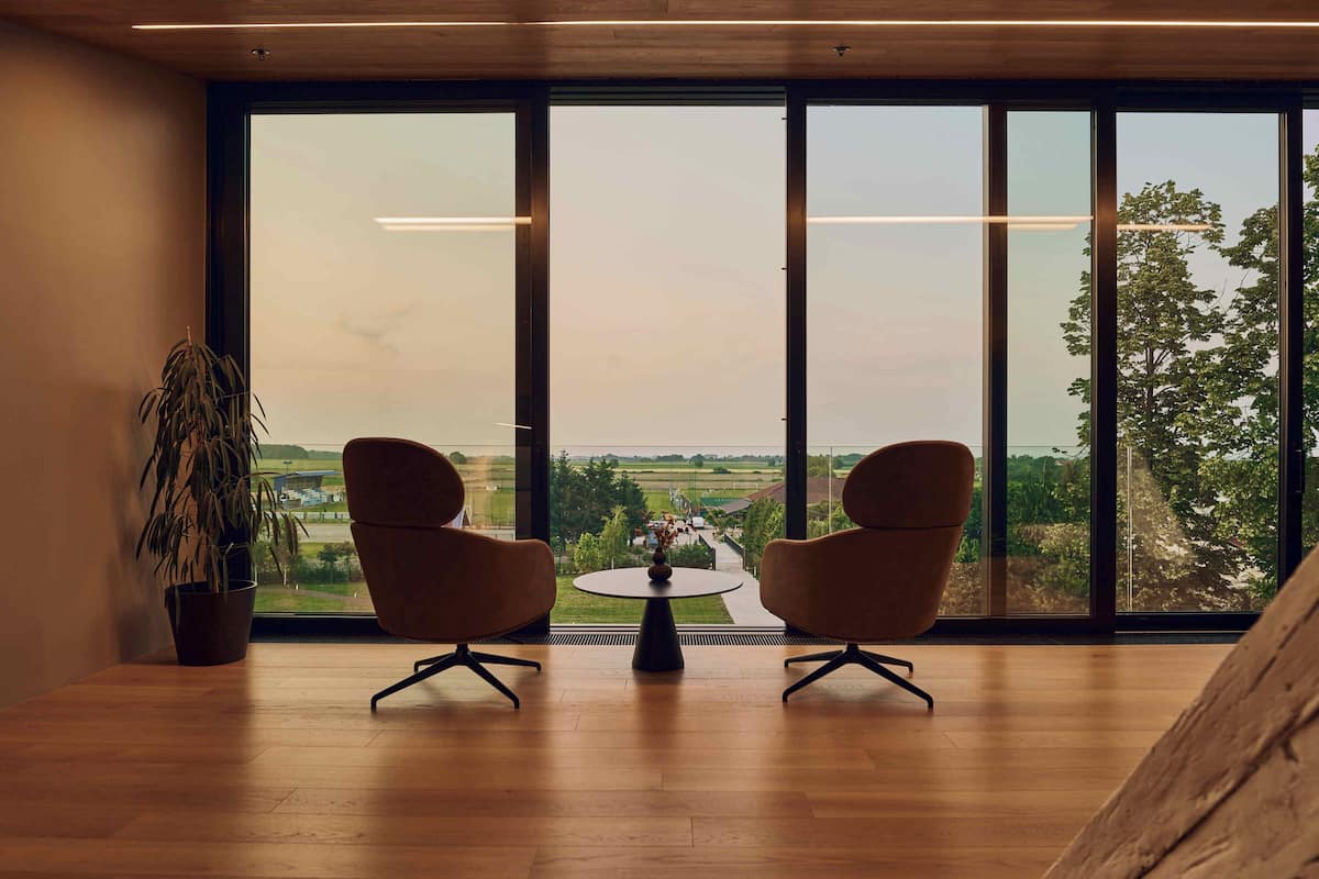 Ein Zimmer mit zwei Stühlen vor einem großen Fenster mit Blick auf die Landschaft.