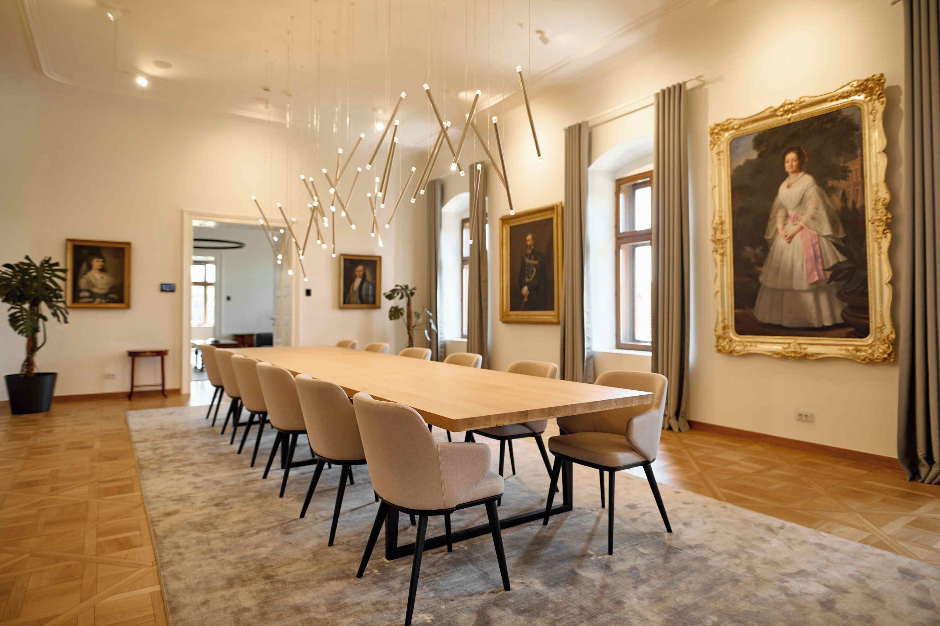 Una sala conferenze con un lungo tavolo, sedie e ritratti incorniciati alle pareti.