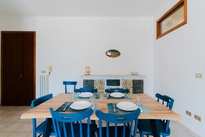 A dining area with a wooden table, blue chairs, white plates, and a decorative tile backsplash.