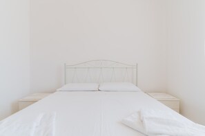 A bed with a metal headboard, two pillows, and a white bedspread.