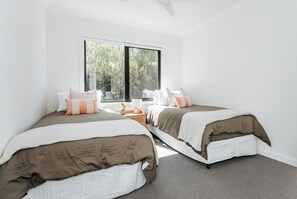 A bedroom with two beds, a large window, and a view of trees.