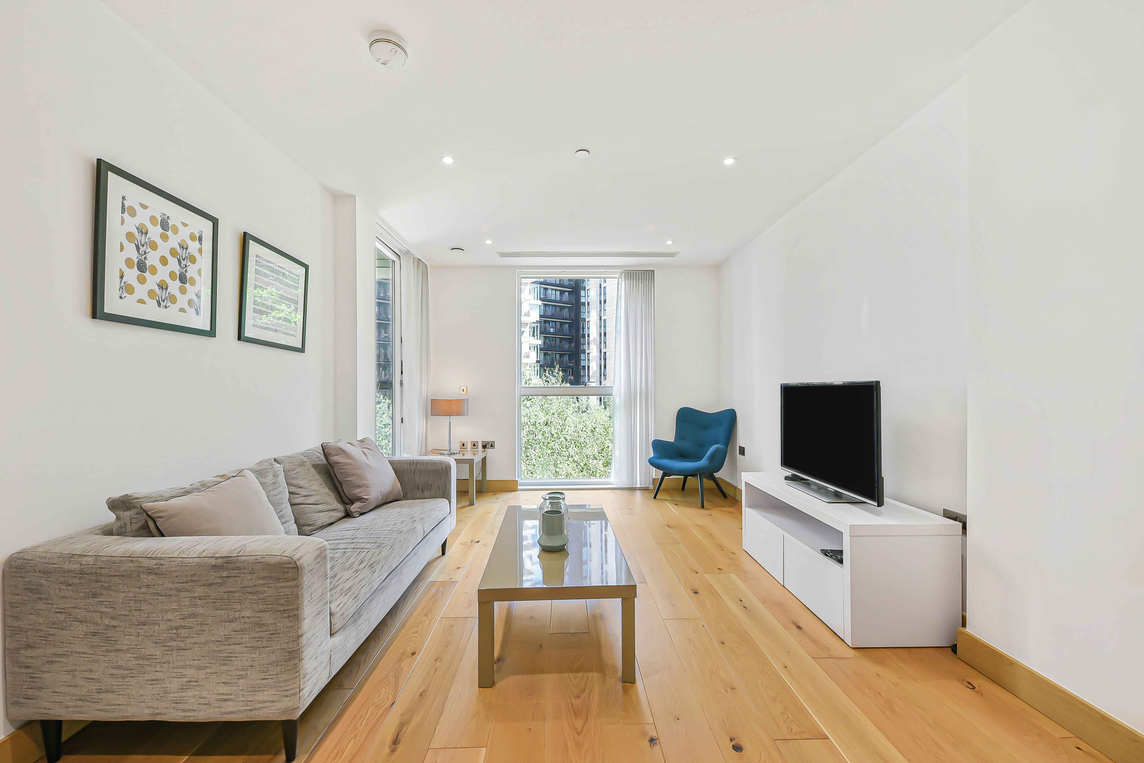 A modern living room with a sofa, coffee table, TV, and artwork on the wall.