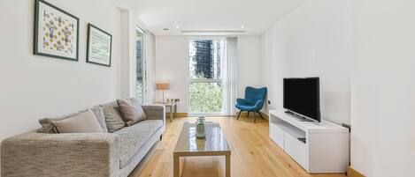 A modern living room with a sofa, coffee table, TV, and artwork on the wall.