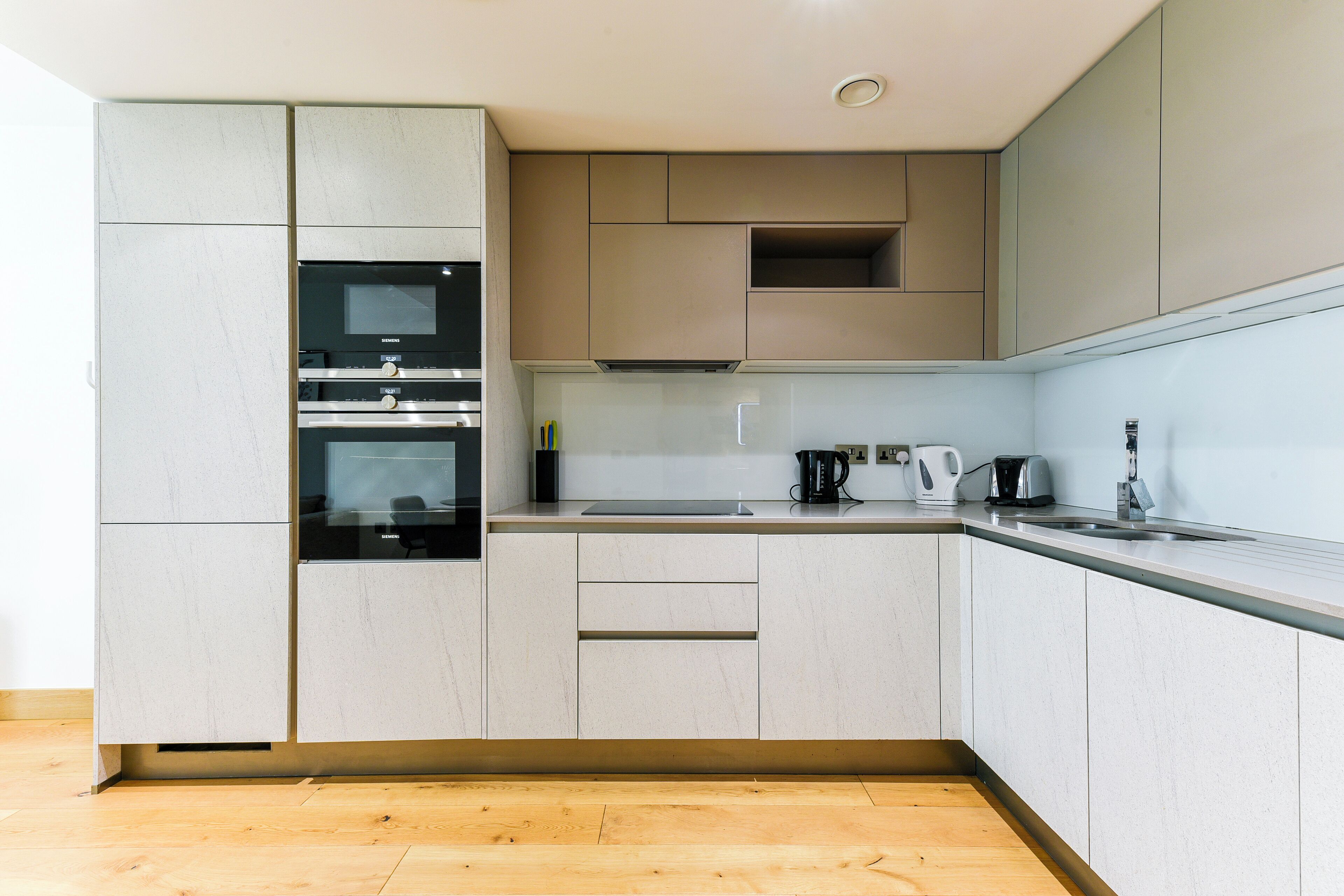 Una cucina moderna con elettrodomestici integrati, un piano di lavoro e pavimento in legno.