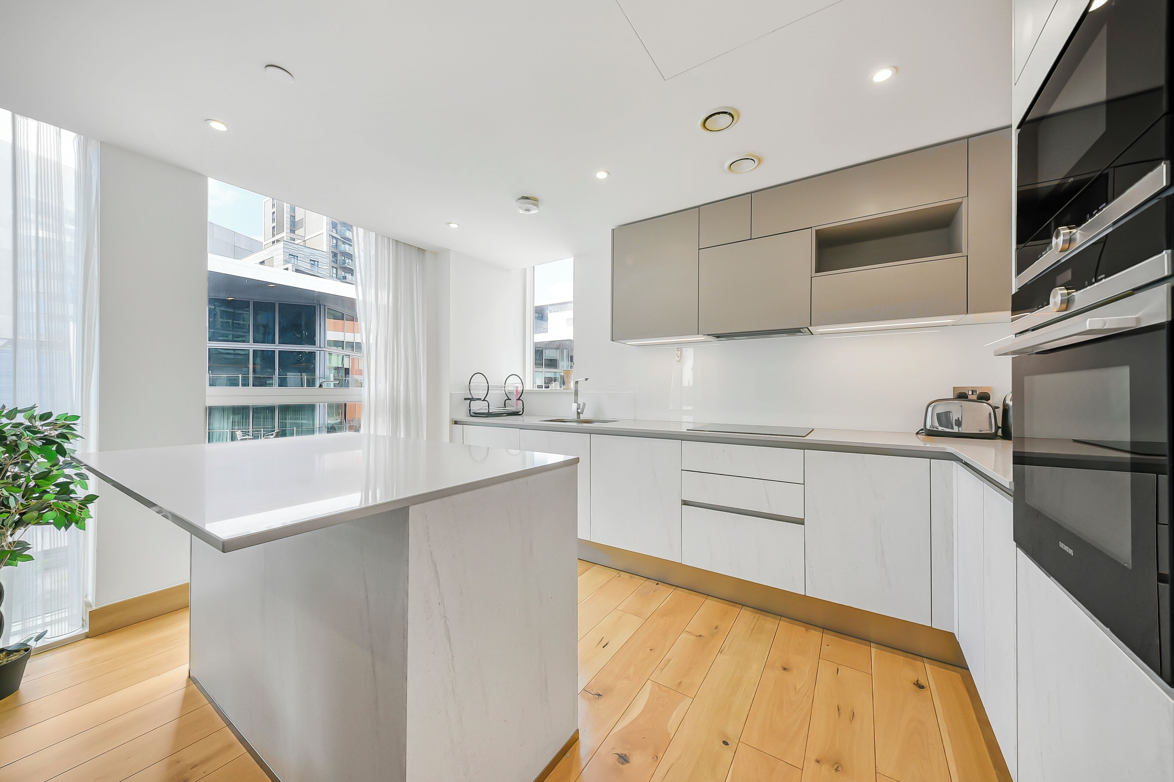 Una cocina moderna con armarios blancos, una isla central y vistas de la ciudad.
