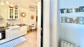 A modern kitchen with white cabinets, a built-in oven, and a dining area with a table and chairs. - Il Sorriso dei Sassi Rooms (Matera)
