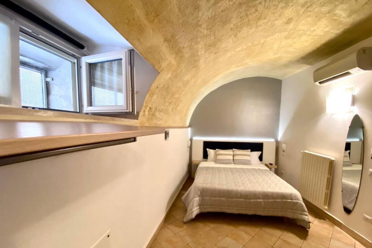 Un dormitori amb un llit, una finestra i un sostre corbat.