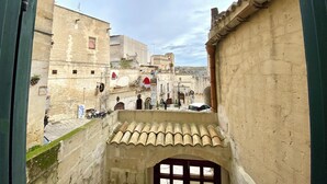 A narrow alleyway with stone buildings, a gate, and a view of a hill in the distance. - Il Sorriso dei Sassi Rooms (Matera)