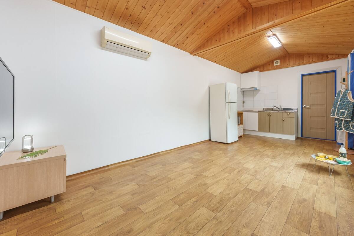 Une cuisine moderne avec un plancher en bois, un four encastré et une fenêtre avec des rideaux.