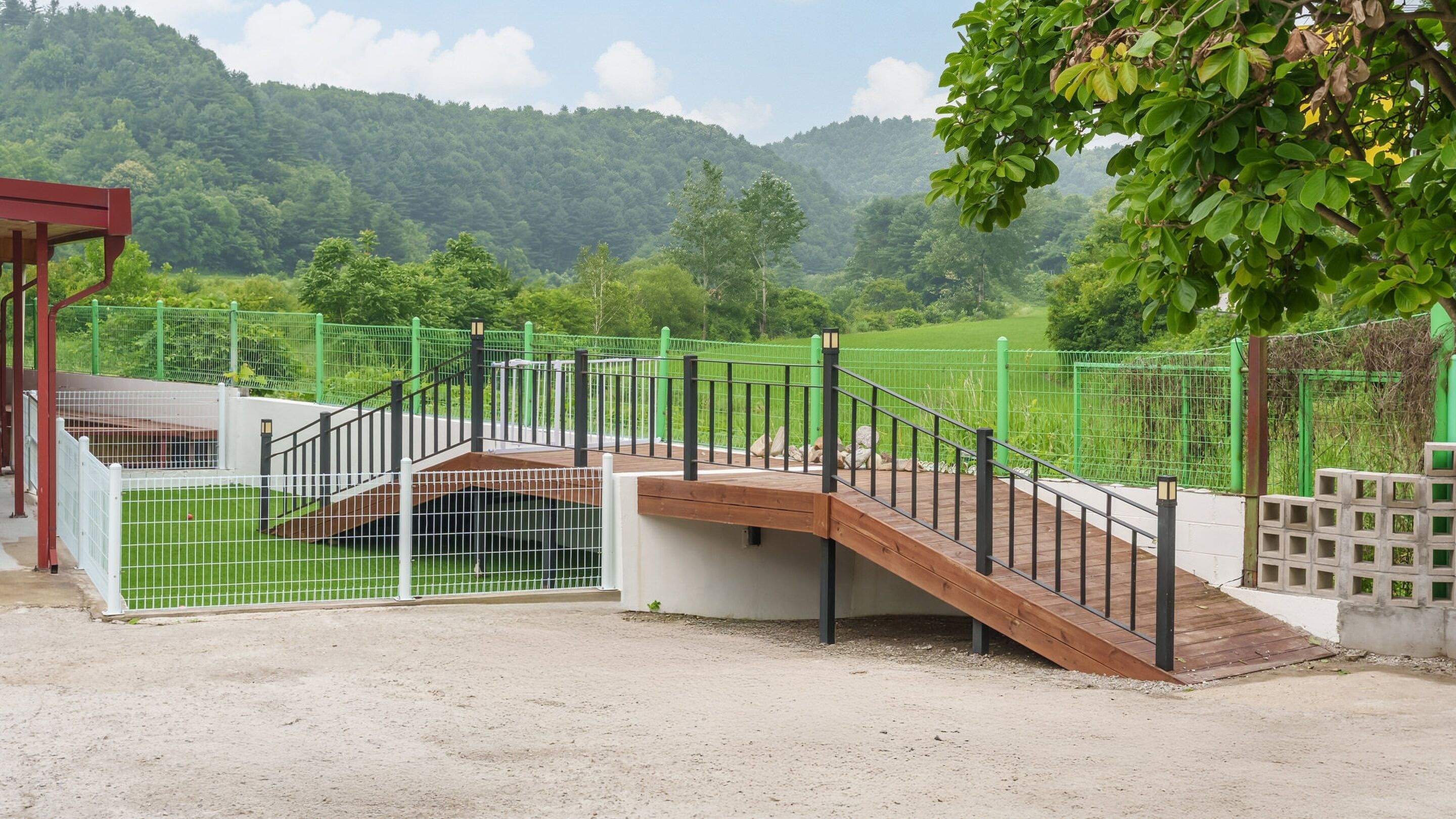 Un área exterior cercada con un puente de madera y una estructura roja.