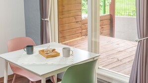 Ein gemütliches Zimmer mit einem weißen Tisch, zwei Stühlen, einer kleinen Ablage mit einem Behälter und Zimtstange sowie einer weißen Tasse.