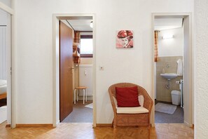 A hallway with a wicker chair, a radiator, and a painting on the wall. - Ferienwohnung 2 mit Balkon – barrierefrei, 2 Schlafzimmer, Küche, Bernau im Schwarzwald (Bernau im Schwarzwald)