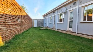 A residential property with a brick wall, a well-maintained lawn, and a modern house with multiple windows and a satellite dish. - Blissful lily lodge (Salima)