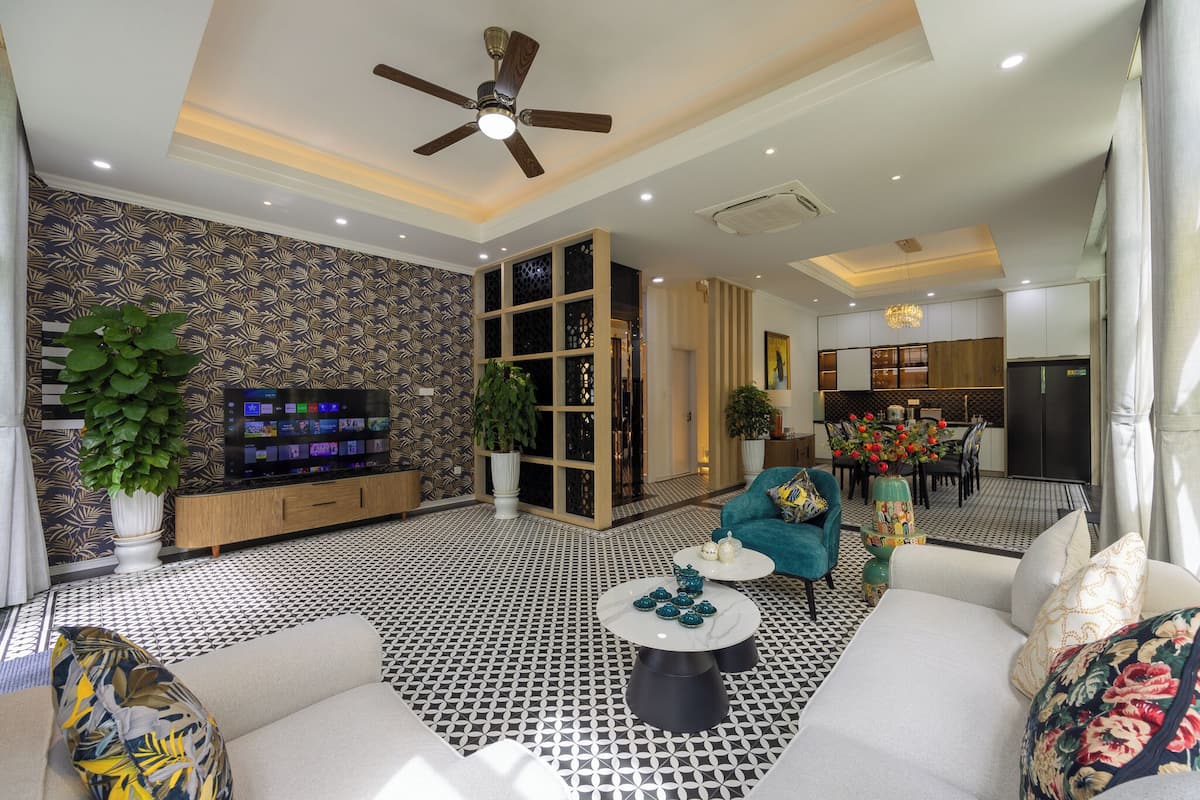 Un salon moderne avec un sol à motifs, un ventilateur de plafond, un téléviseur et un coin repas agrémenté d  ’un lustre.