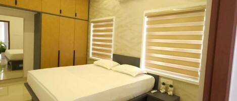 A modern bedroom with a bed, bedside tables, an air conditioning unit, and a ceiling fan.