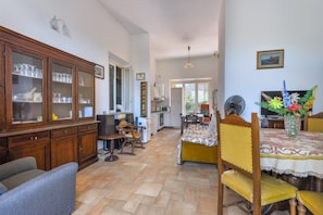 A spacious living area with a dining table, chairs, a sofa, and a cabinet with glass doors.