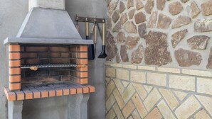 An outdoor brick oven with a stone wall backdrop.