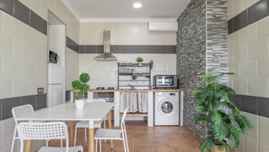 A compact kitchen with a washing machine, a microwave, and a small dining area with chairs and a table.