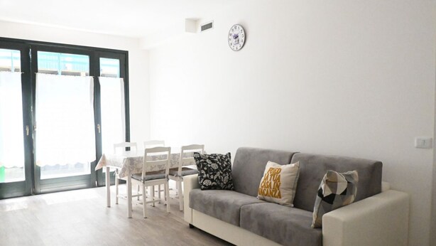Ein Wohnzimmer mit einer Couch, Sesseln, einem Tisch und einer Wanduhr.