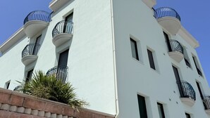 Ein mehrstöckiges Gebäude mit Balkonen und Fenstern vor blauem Himmel.