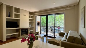 Un salon avec une cheminée, un téléviseur et un coin repas comprenant une table et des chaises.