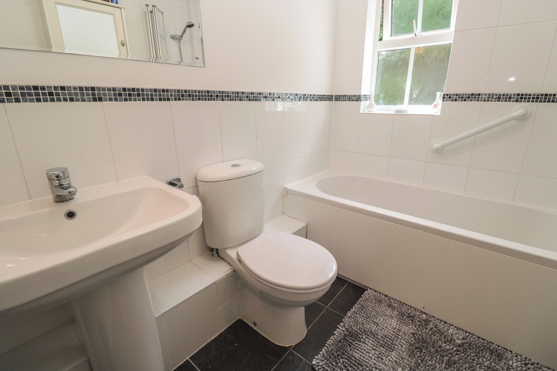 Et badeværelse med vask, toilet og badekar.