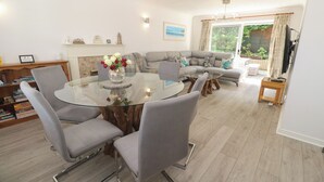 Una sala de estar moderna con una mesa de comedor de vidrio, sofás grises y una chimenea.