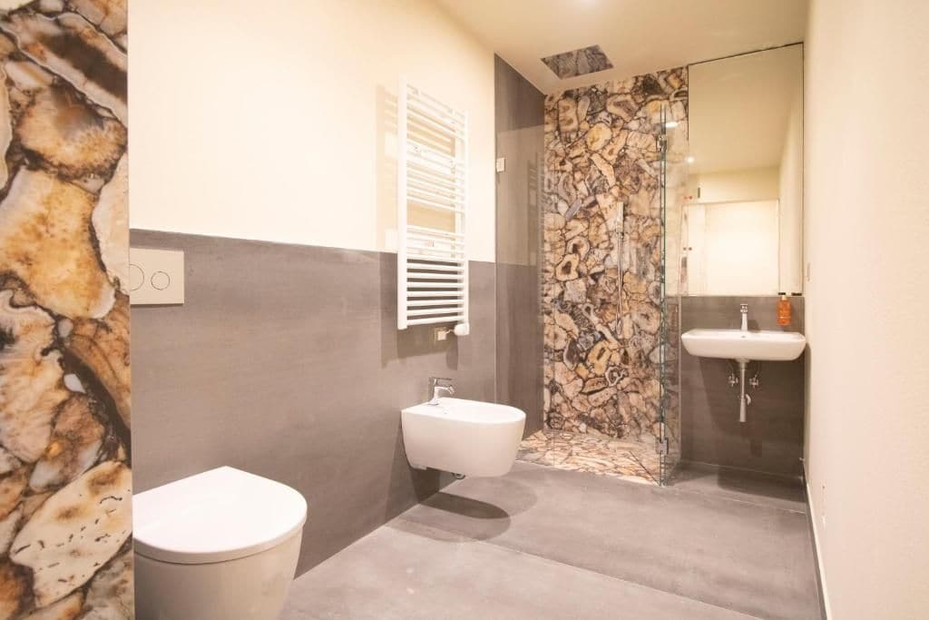 Ein Badezimmer mit einer Steinwand, einem weißen Waschbecken und einer Toilette.