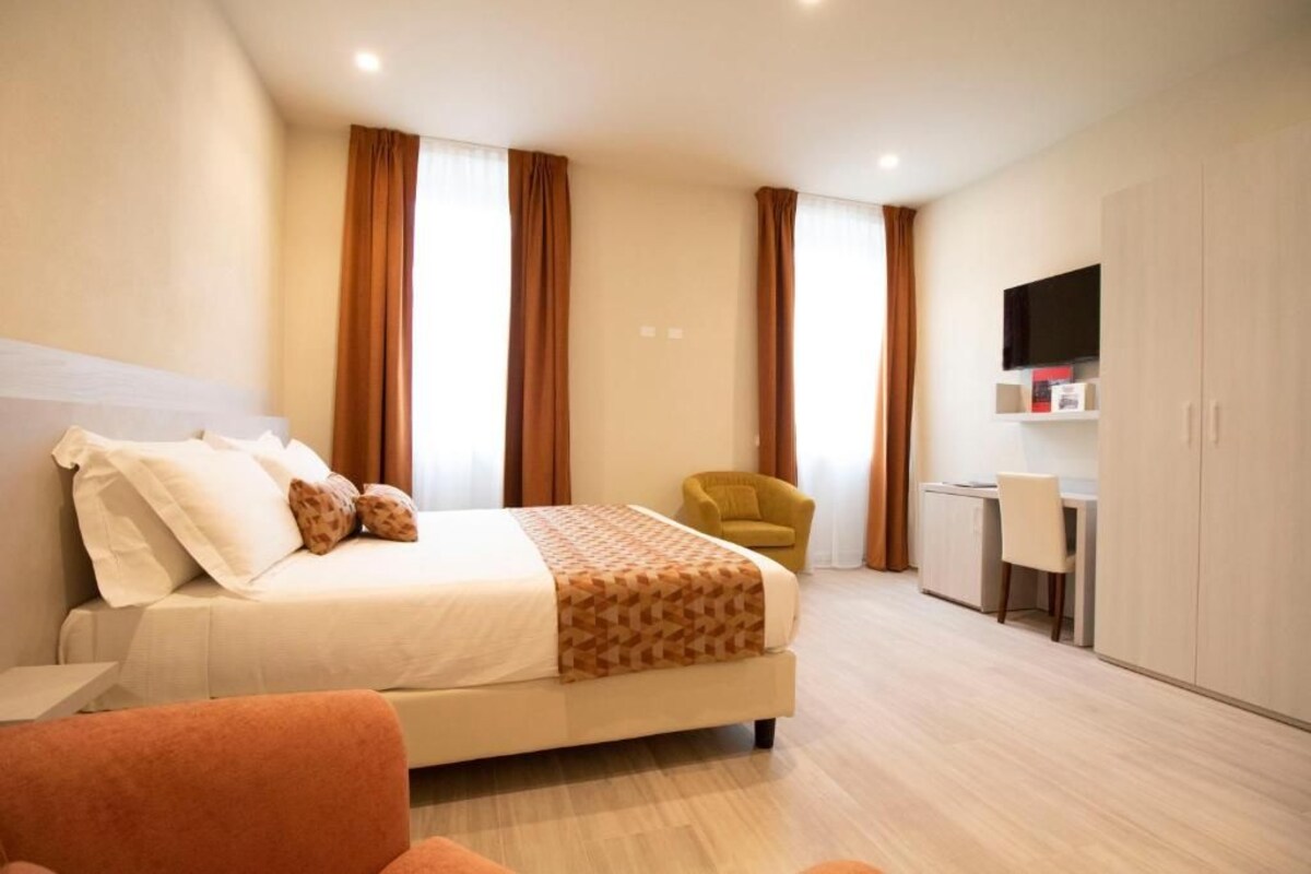 Una camera d'albergo con un letto, una scrivania, una sedia e un armadio.