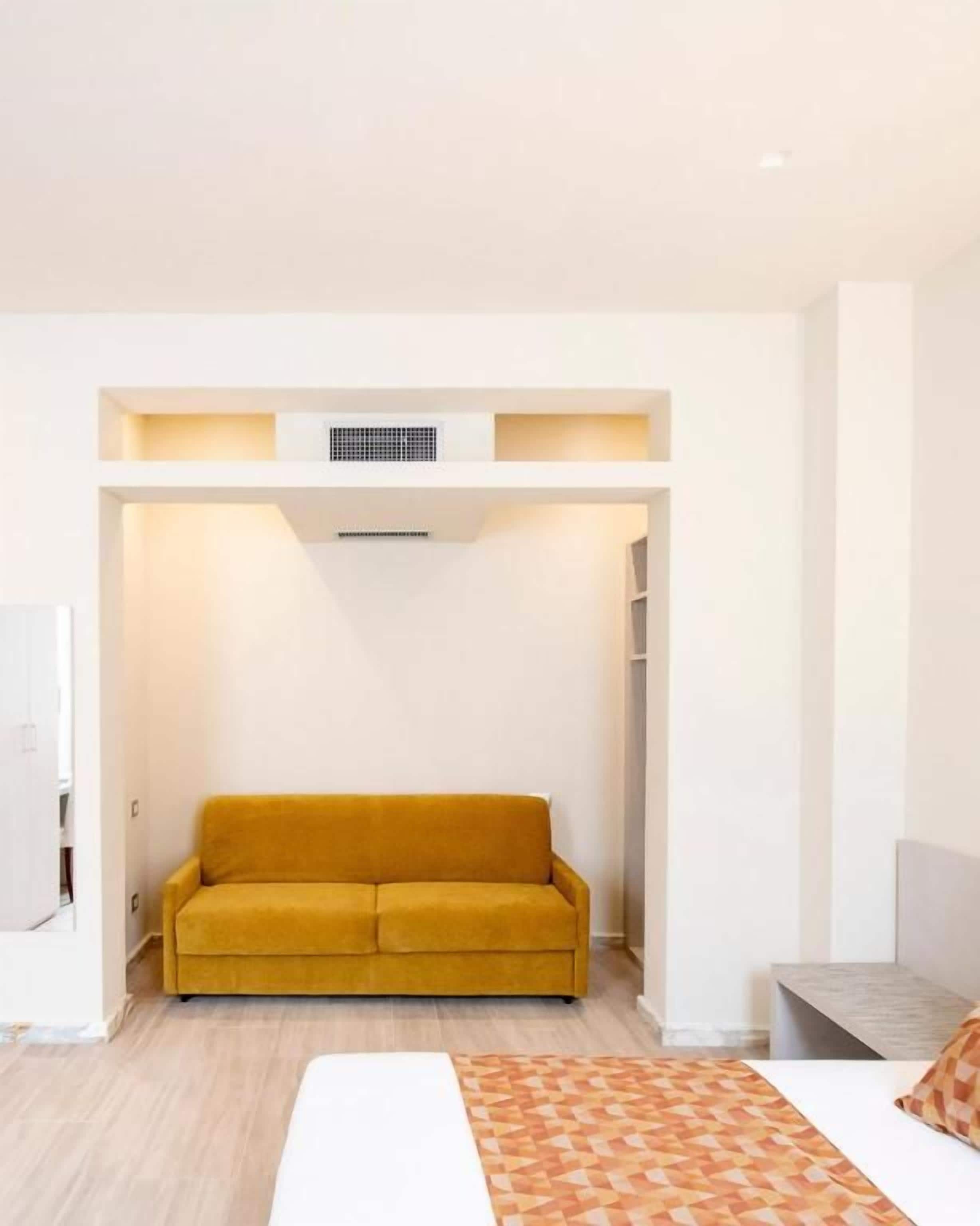 Ein modernes Hotelzimmer mit einer Couch, einem Bett und einem kleinen Tisch.