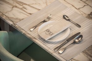 Una mesa dispuesta con un plato, cubiertos y una servilleta sobre un mantel individual.