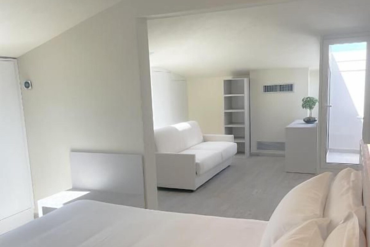 Una camera da letto con un letto grande, un armadio bianco e un comodino.