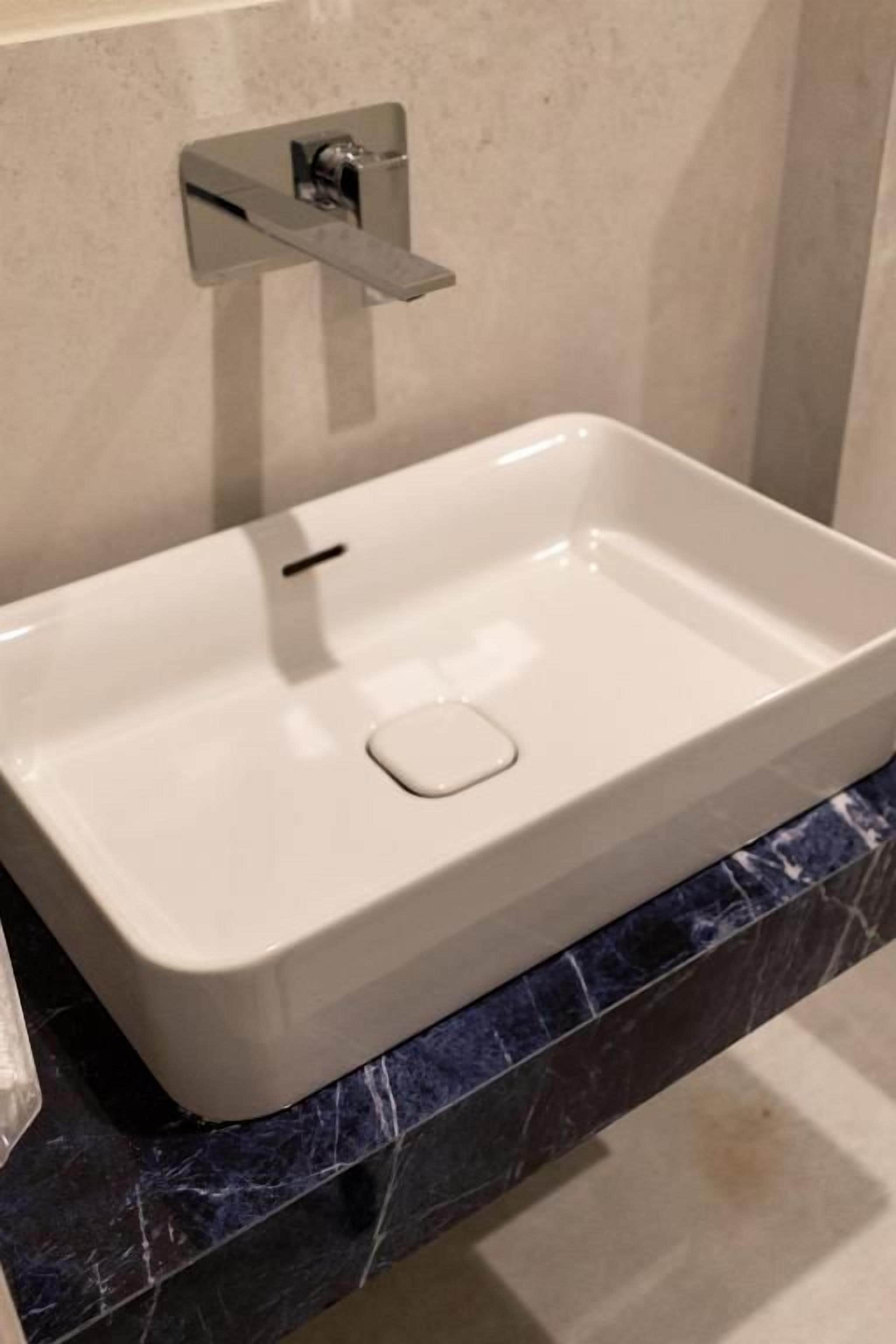 A bathroom with a white sink, a faucet, and a marble countertop.