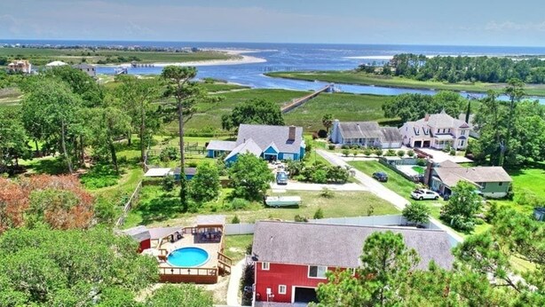 Un quartier résidentiel situé sur la côte, comprenant plusieurs maisons, une piscine et offrant une vue sur l’océan.