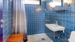 A bathroom with blue tiles, a shower, a sink, and a wooden bench. - "Ognen" - 800m from the sea by Interhome (Væggerløse)