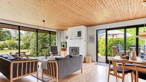 A modern living room with a fireplace, large windows, and a dining area with outdoor seating. - "Ognen" - 800m from the sea by Interhome (Væggerløse)