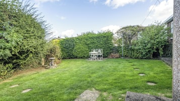 A well-maintained garden with a lawn, a stone pathway, and a metal table with chairs.
