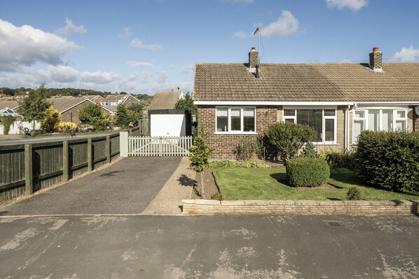 A residential house with a front driveway, a fenced yard, and a clear sky. - 2 Bed - Sleeps 4 - Parking - Pet Friendly (Filey)
