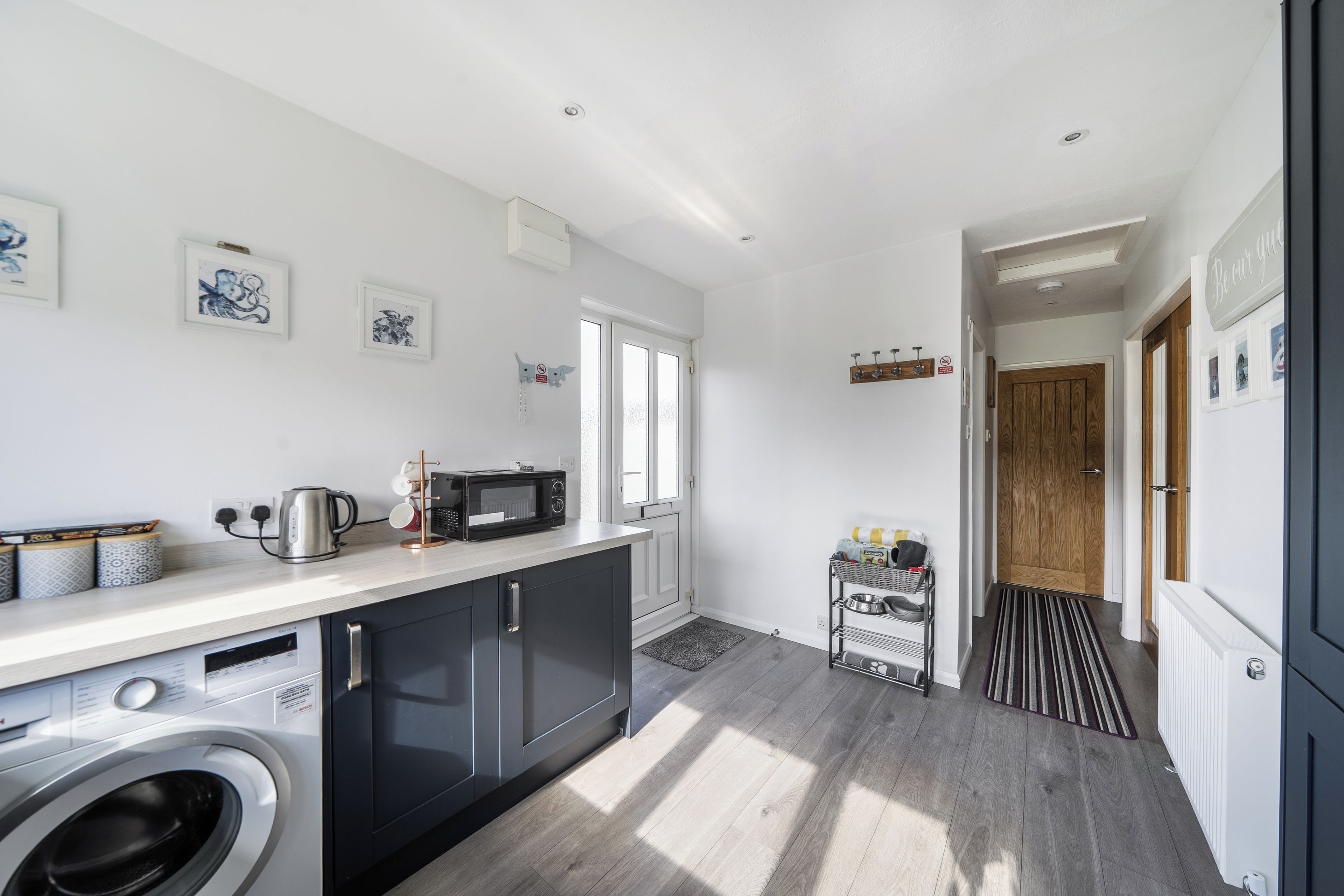 A modern kitchen with a washing machine, microwave, and kettle.