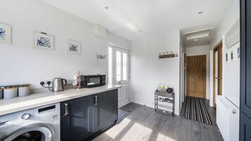 A modern kitchen with a washing machine, microwave, and kettle.